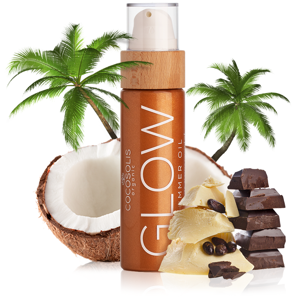 A bottle of COCOSOLIS Glow Shimmer Oil surrounded by palm trees, coconuts, and chocolate