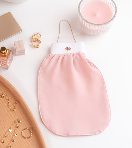 A COCOSOLIS Exfoliating Mitt on a counter surrounded by jewelry