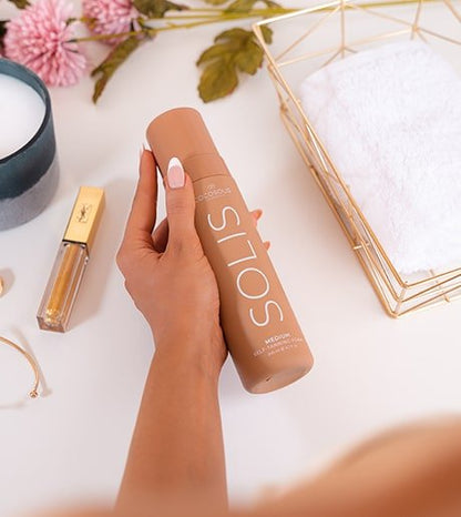 Cocosolis SOLIS self-tanning foam bottle being held for application